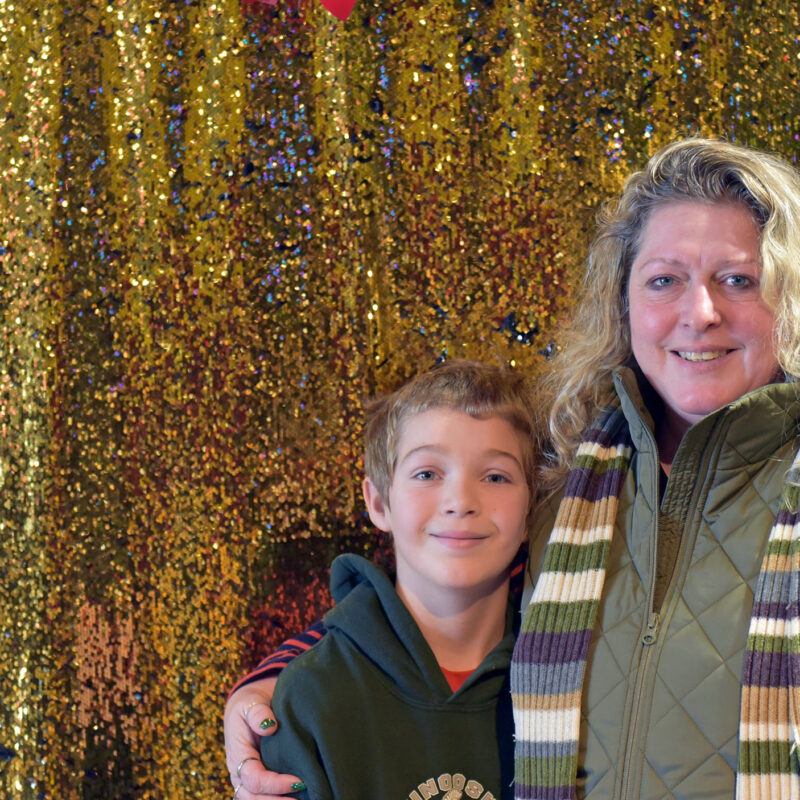 a mom and her son pose in front of a gold glitter backdrop