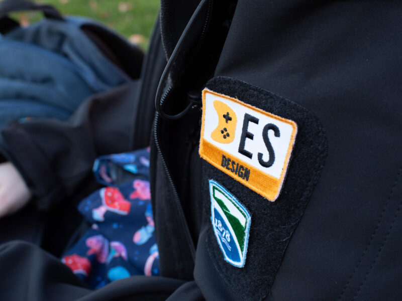 Close up photo of a student wearing a Game design jacket outside with patches