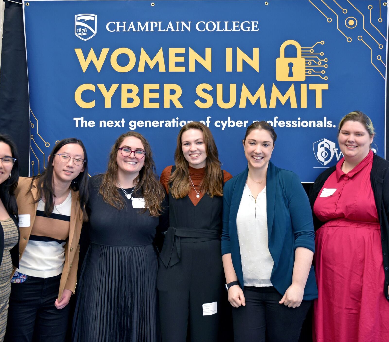 a small group of students pose in front of the woman in cyber summit sign