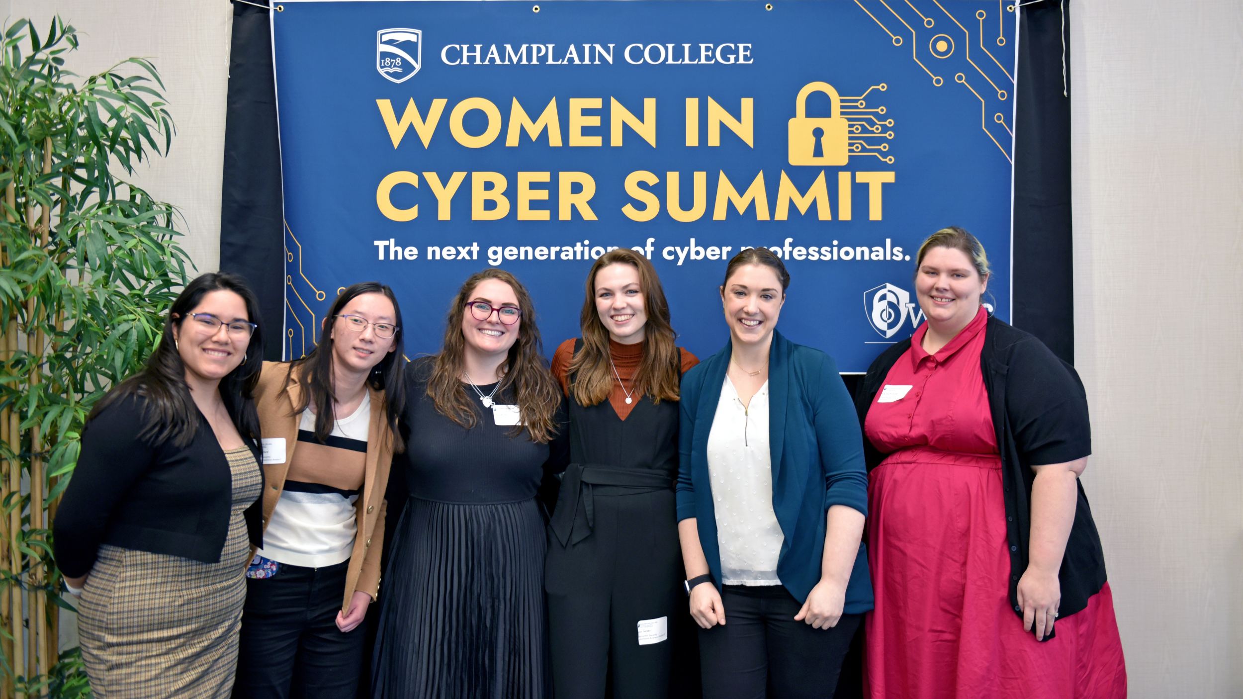 a small group of students pose in front of the woman in cyber summit sign