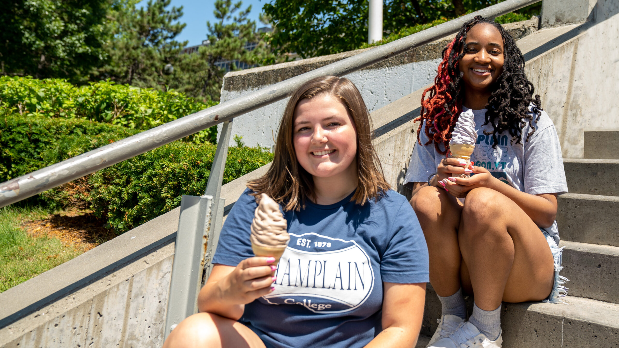 two students sit on stairs outside eating ice cream cones