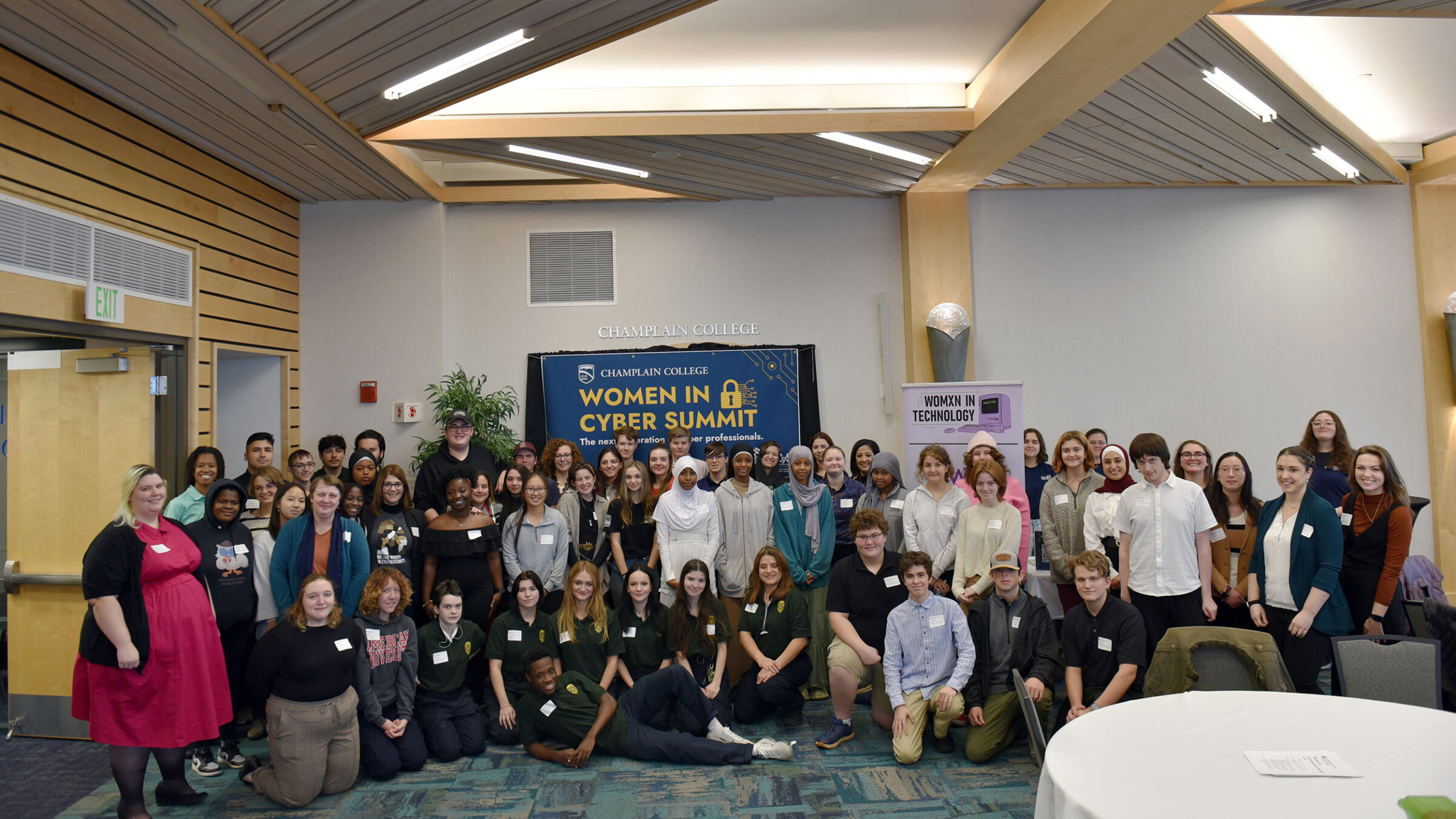 more than 70 people pose for a photo in front of a women in cyber summit sign