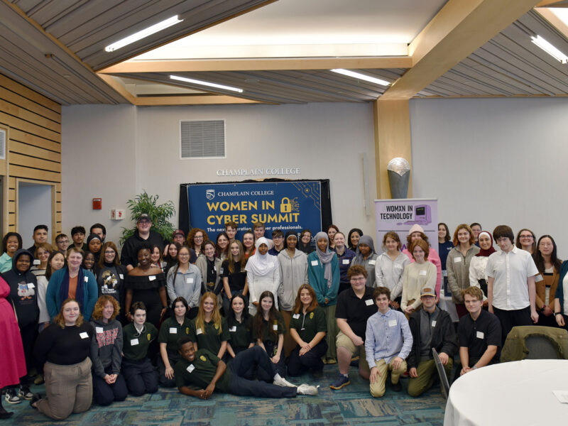 more than 70 people pose for a photo in front of a women in cyber summit sign