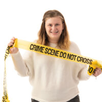 Cara Benjamin holds "Crime Scene Do Not Cross" tape