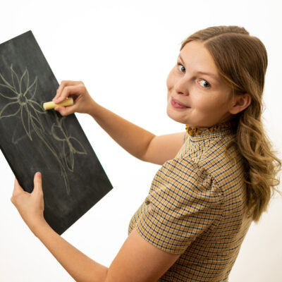 Emma Dannenberg draws a flower on a chalk board