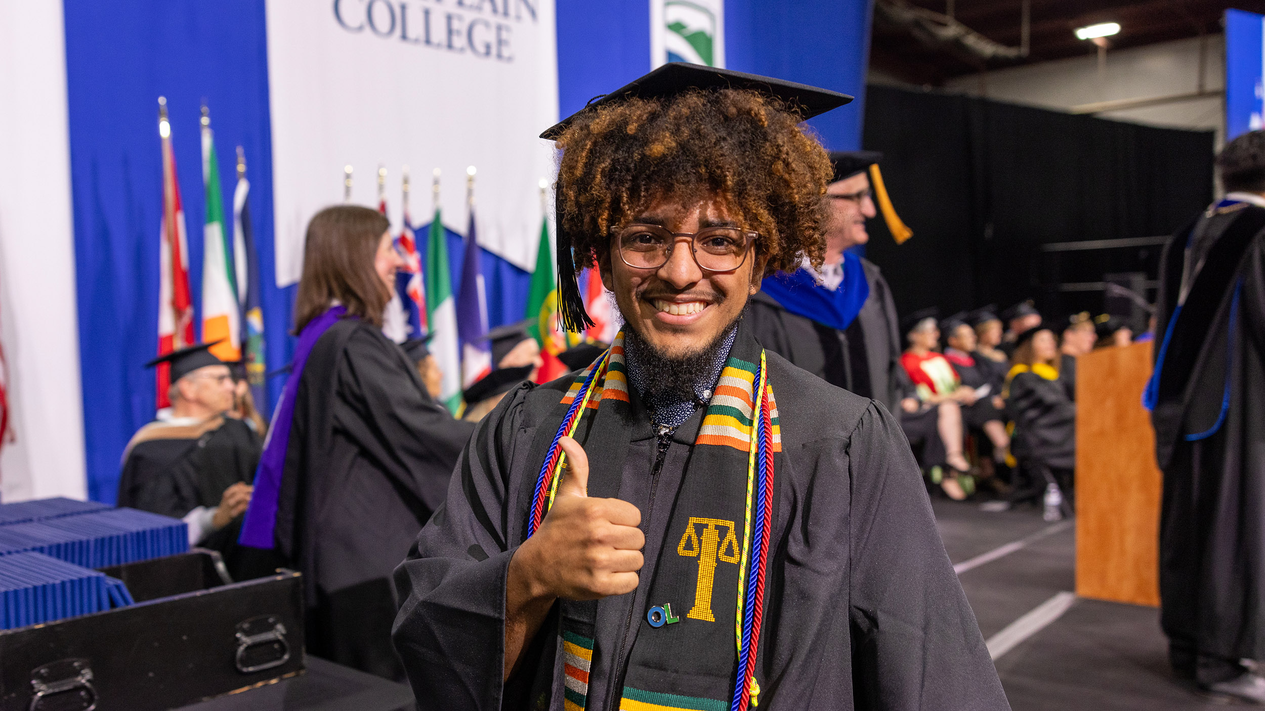 new graduate gives the camera a thumbs up and a smile