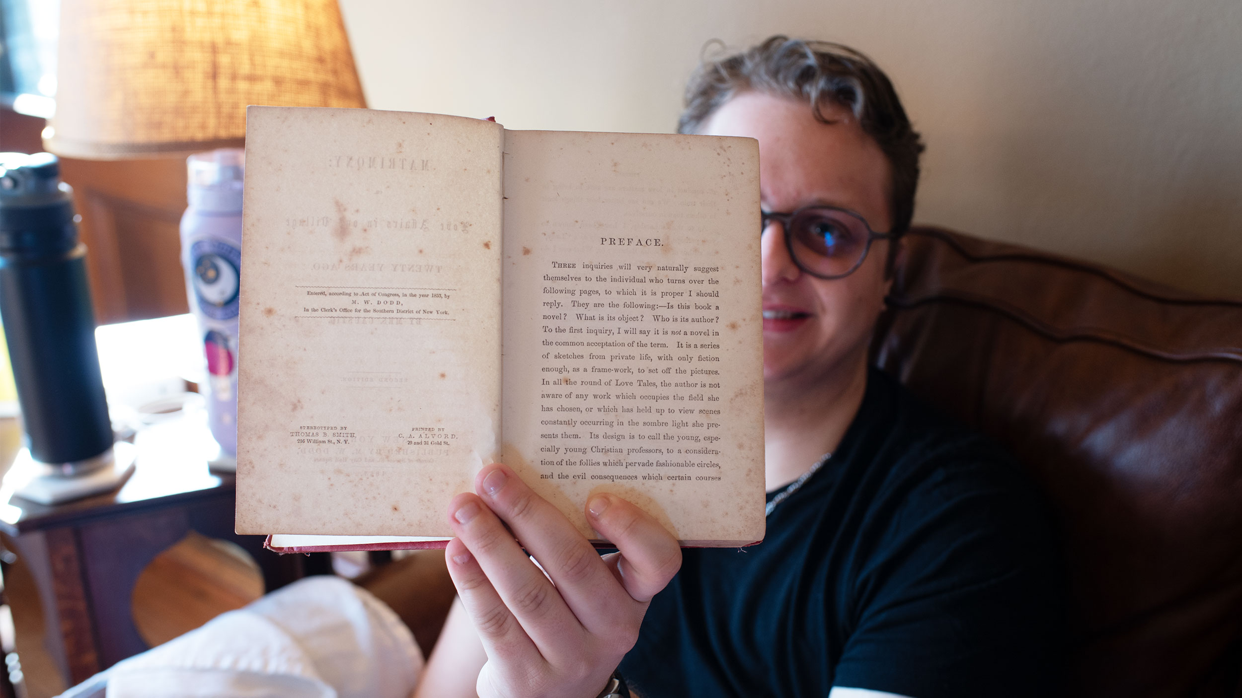 student holds an old warped book open for a close up look