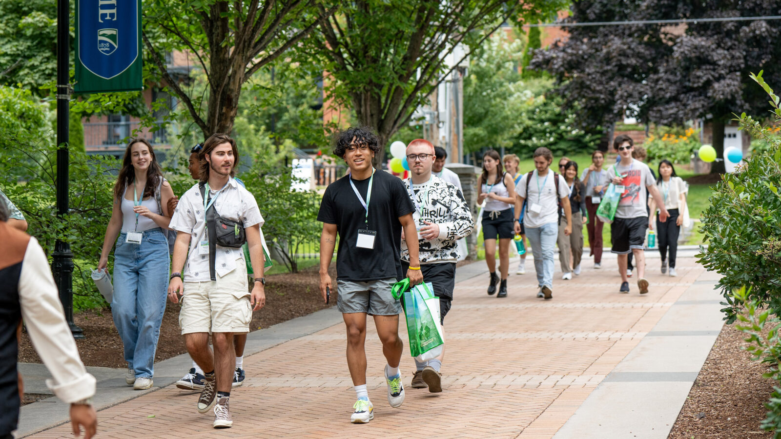 large group of students walk across campus