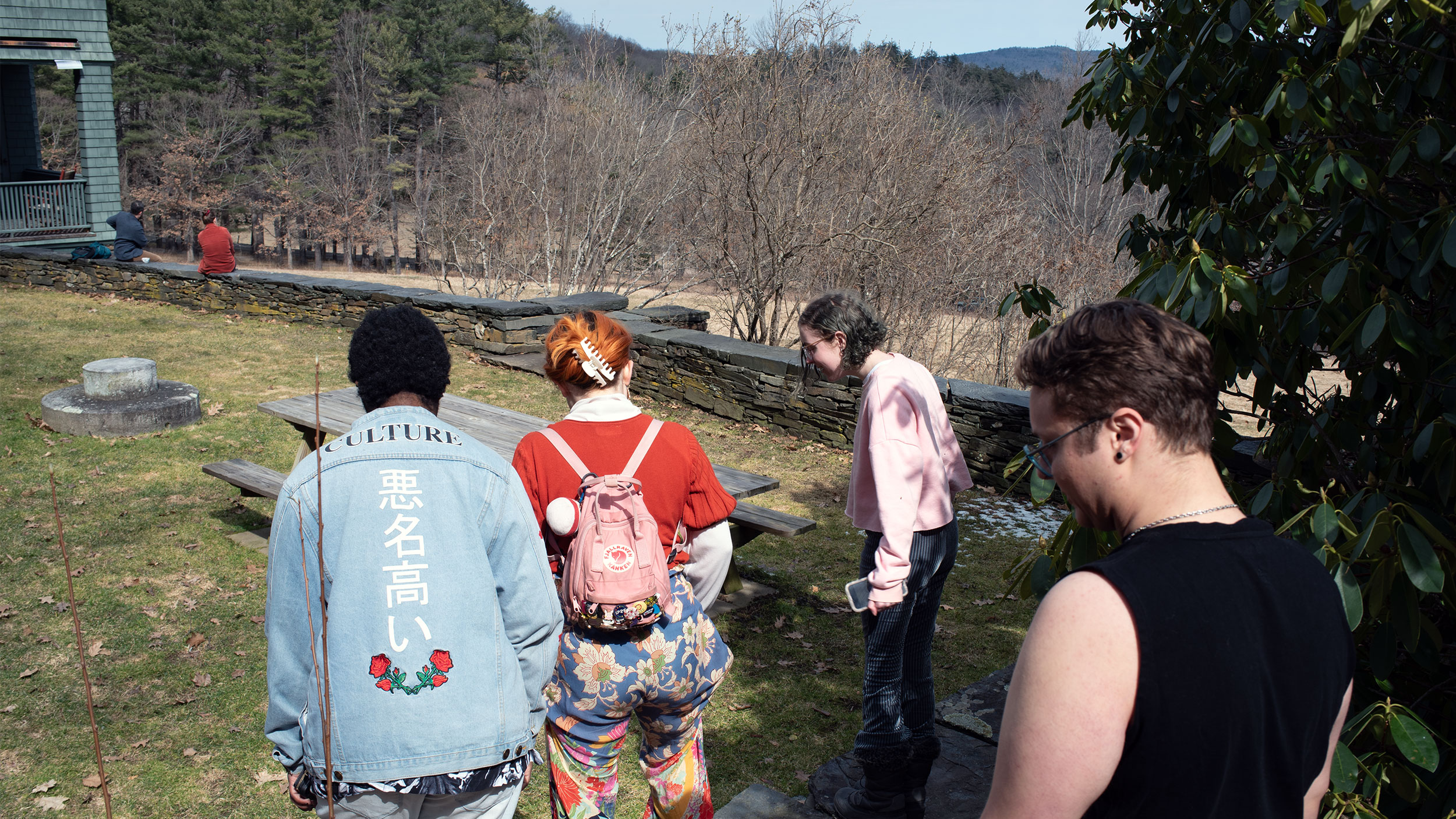 four students look at the grass while walking around an estate in rural vermont