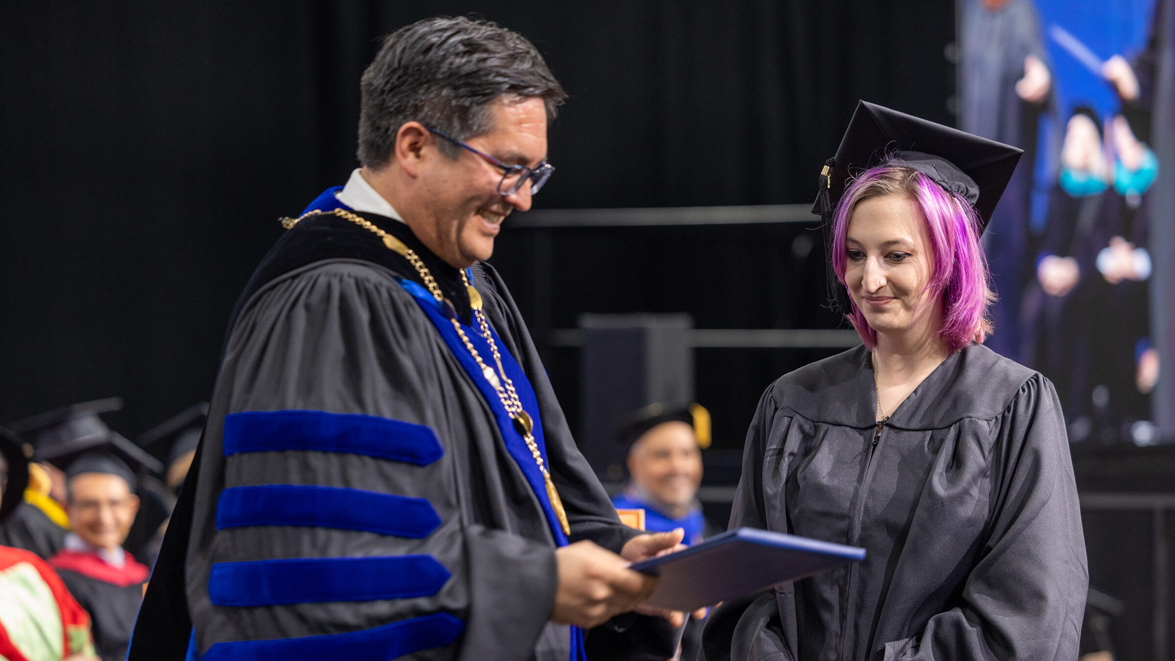 President Hernandez presents a diploma to the graduating senior