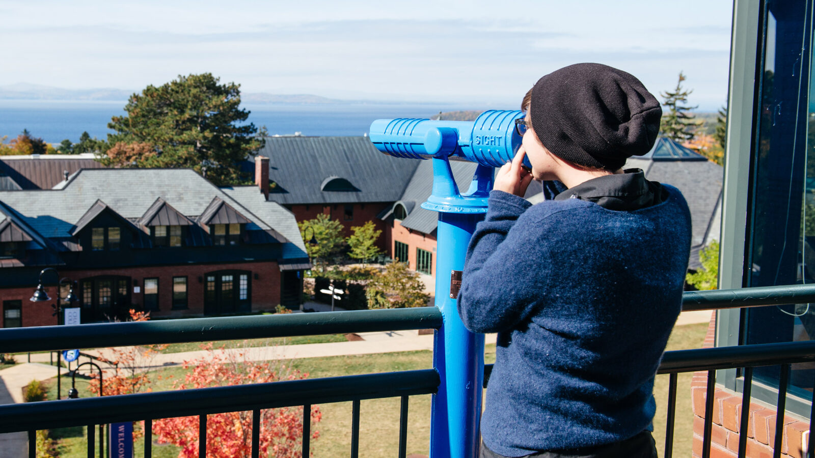 students looks through the telescope on a balcony to view Lake Champlain