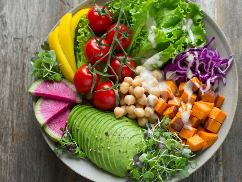 plate of bright healthy foods including lettuce, peppers, tomatoes, avocado, chickpeas, and more