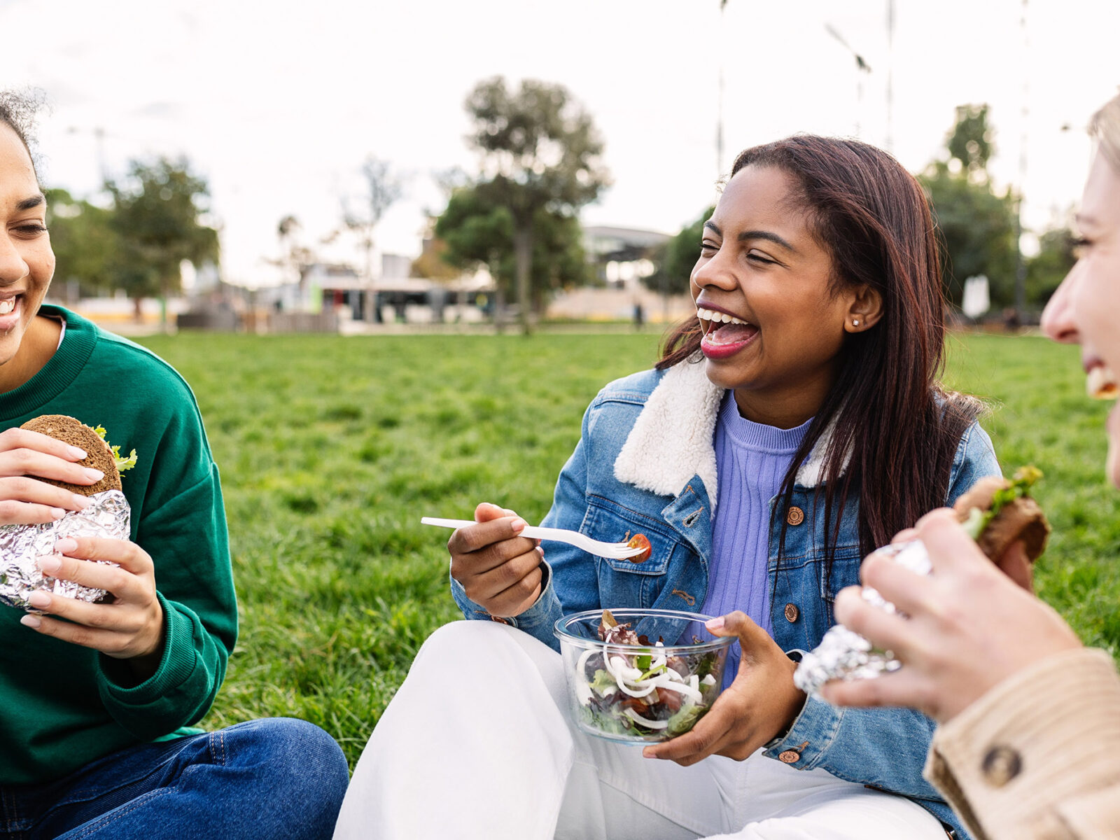 Young group of happy diverse women having lunch at green park campus college after classes