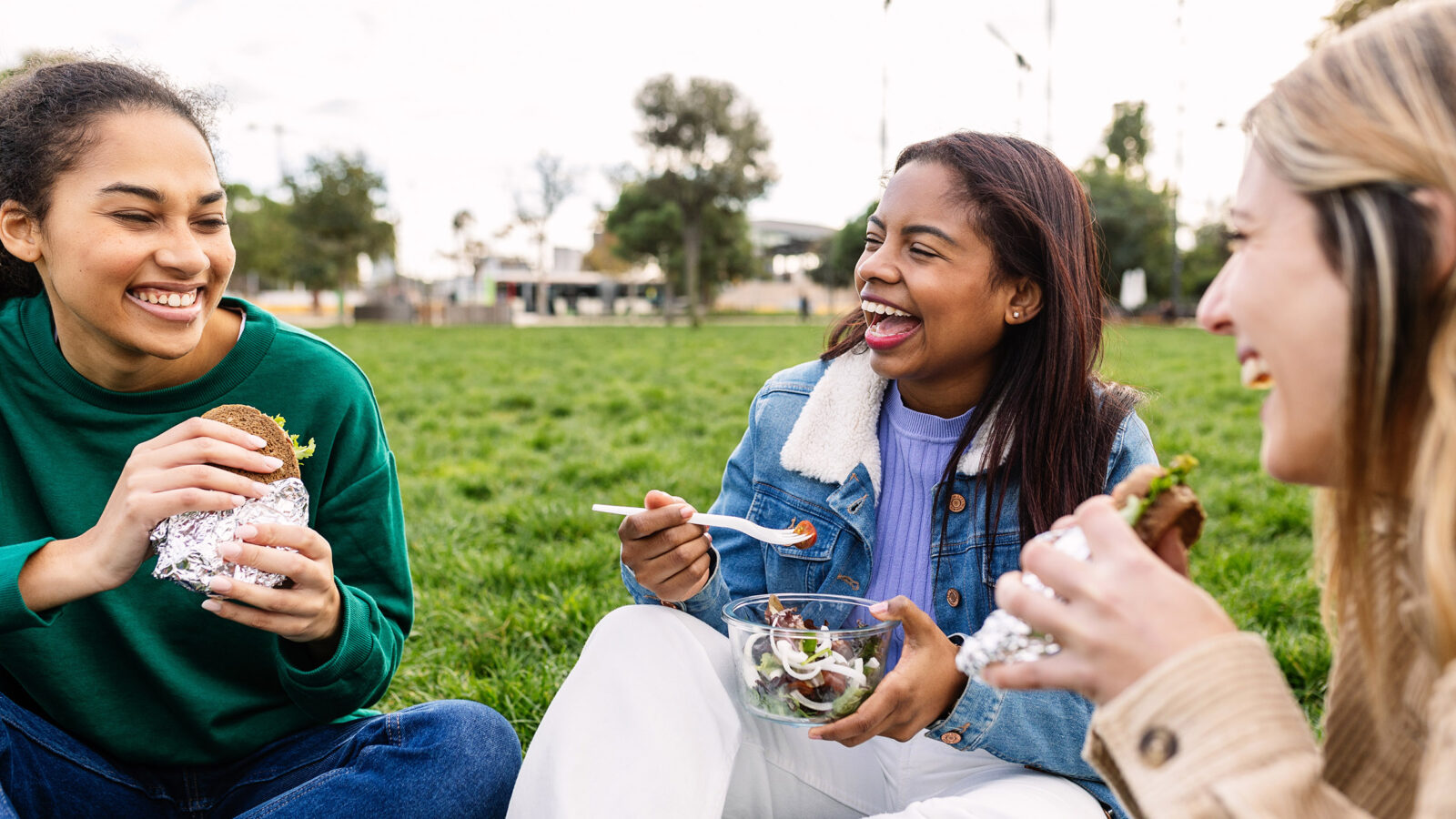 Young group of happy diverse women having lunch at green park campus college after classes