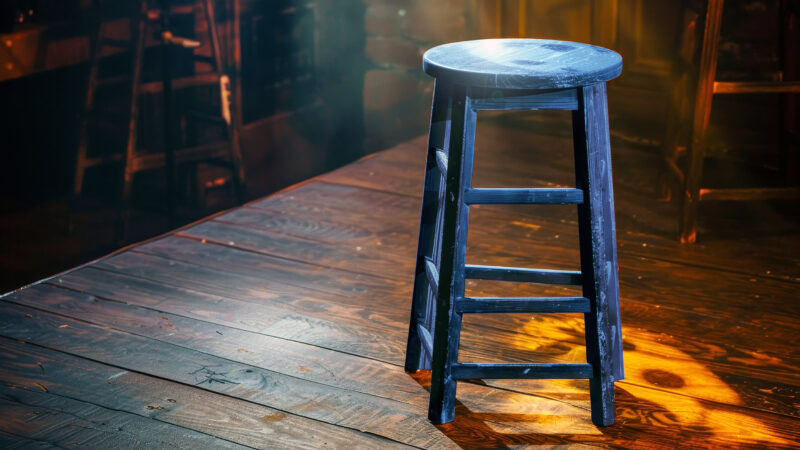 a blue stool sits on a stage in the spotlight