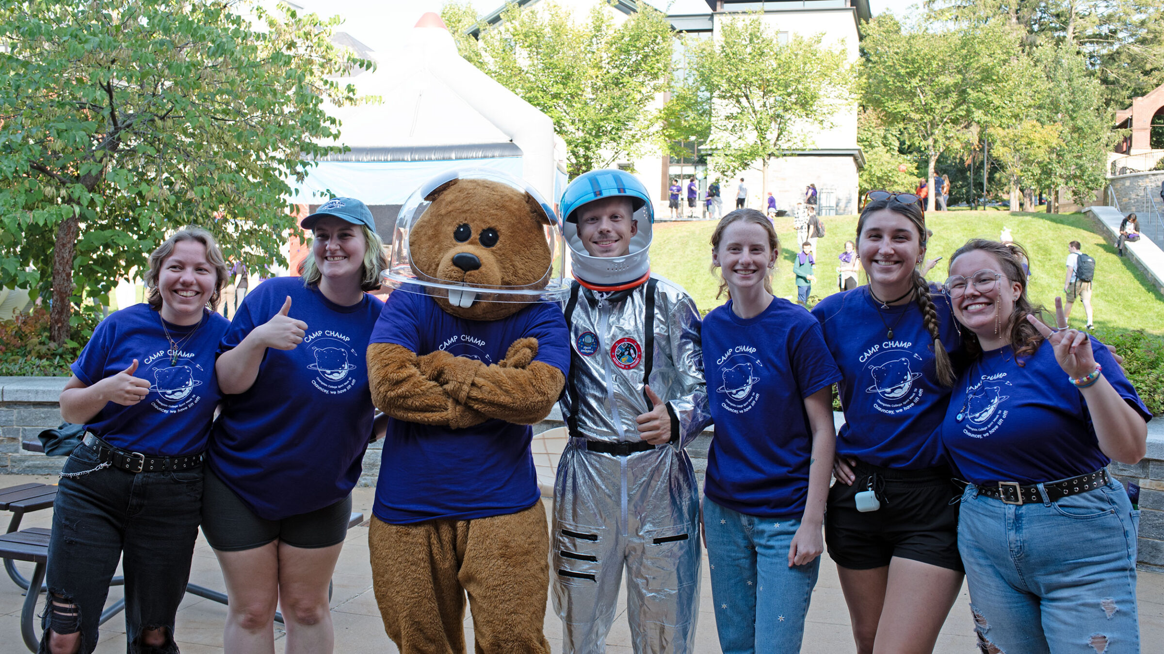 Five students who are part of CHAMP pose for a photo in purple t-shirts with Chauncey T Beaver. One student is in a silver astronaut costume.