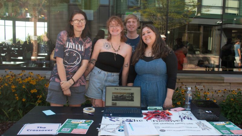 students smiling behind the sign up table for the Crossover, a student publication at the activities fair