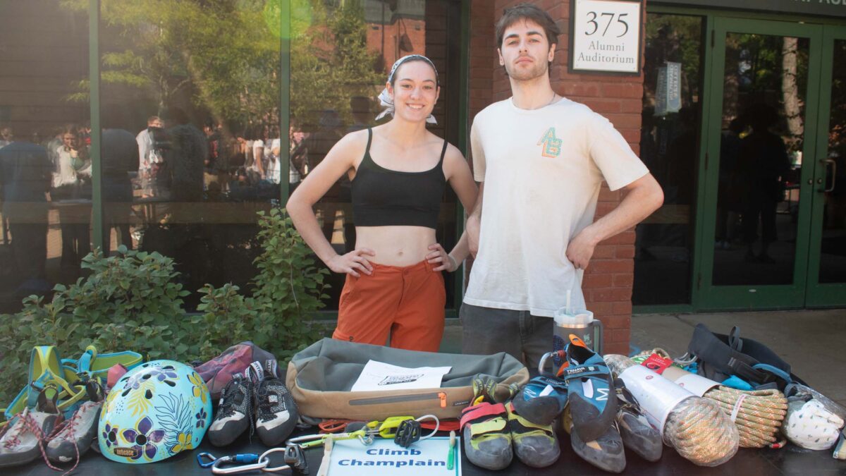 students in the rock climbing club posing behind a table at the club fair with rock climbing equipment