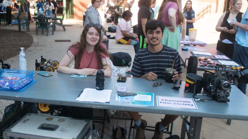 students sitting behind the Champlain film society club table at the activity fair with film equipment