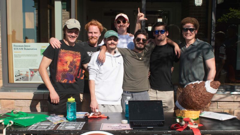 students in the flag football club posing behind their table at the club and activities fair