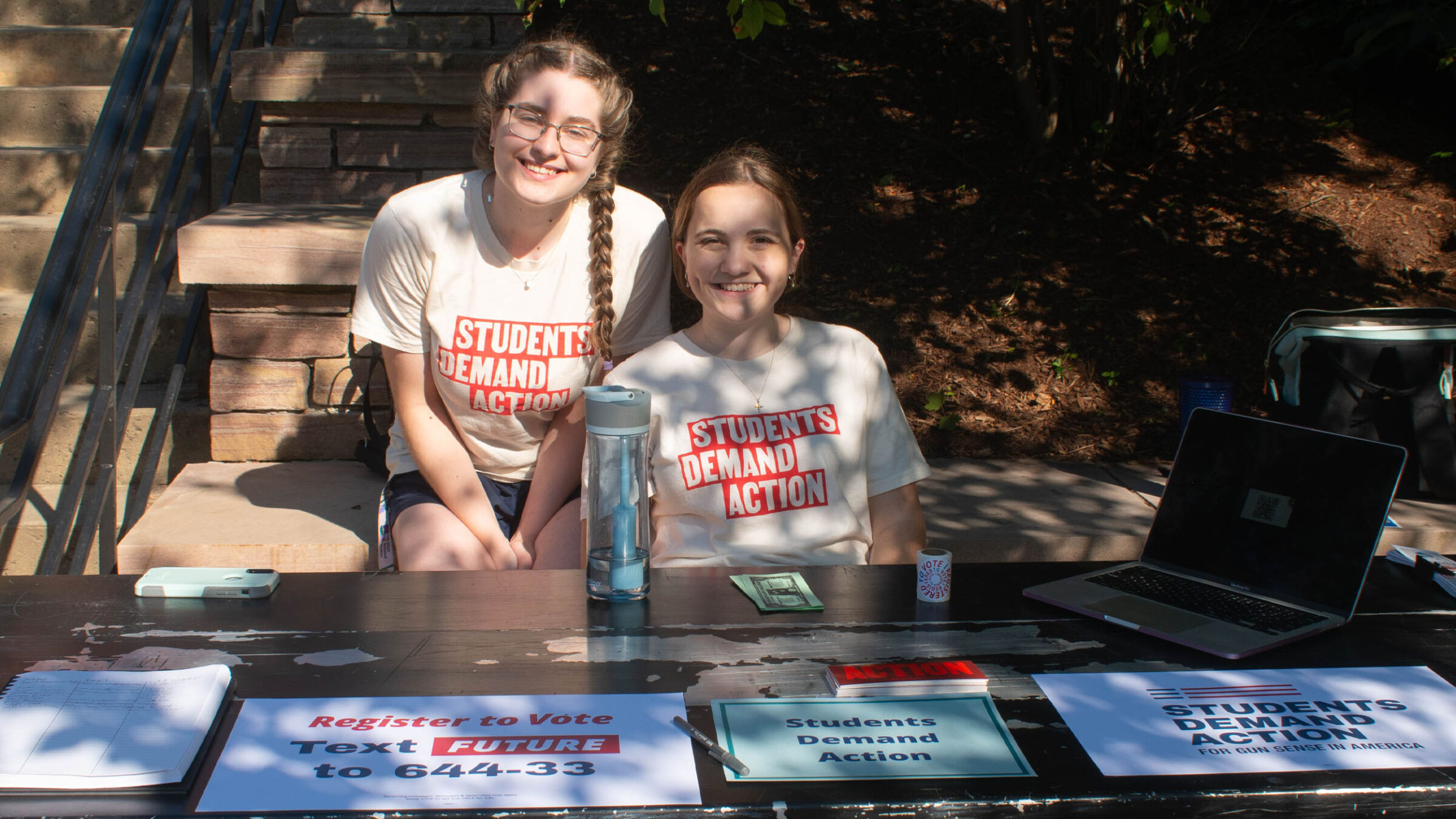 two students in the students demand action club sitting behind their club table at the activity fair