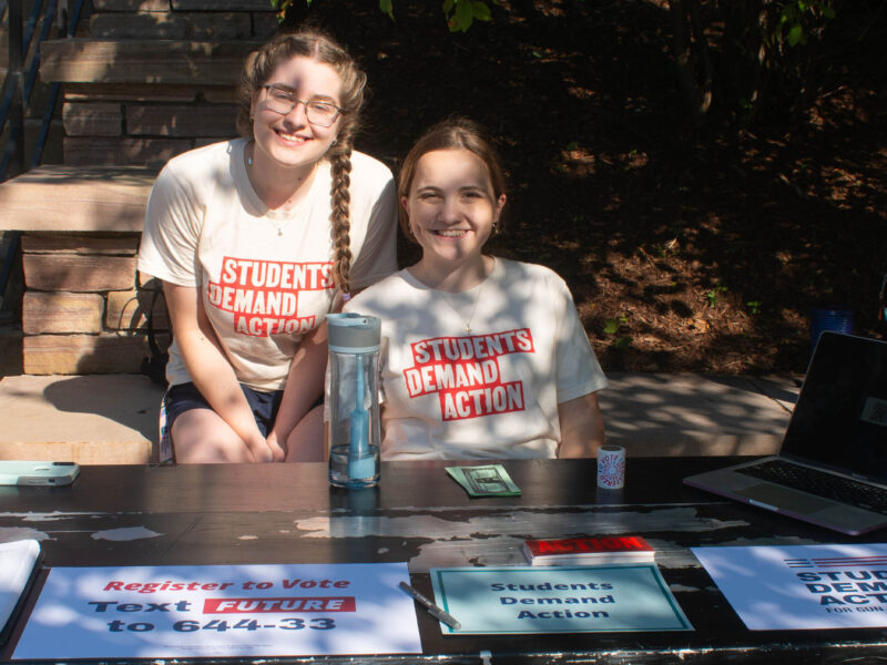 two students in the students demand action club sitting behind their club table at the activity fair