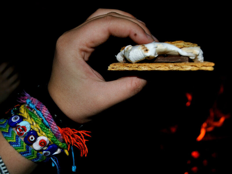 a person holding a smore wearing bracelets in the dark