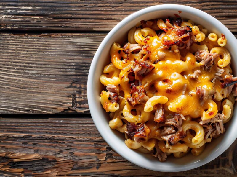 pulled pork and mac and cheese in a white bowl on a wooden table background