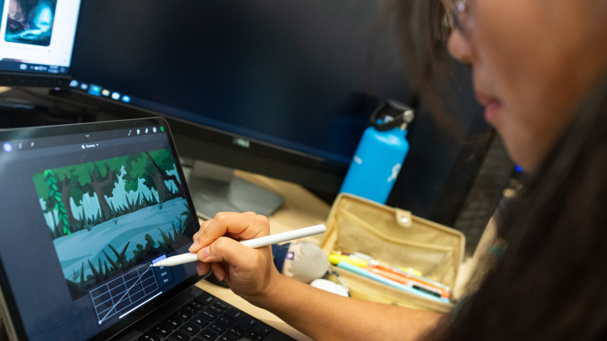 a student using an IPad and apple pencil to create digital art in a classroom