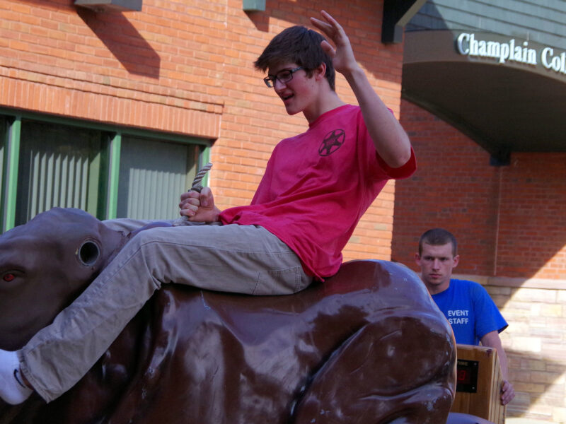 a student riding a mechanical bull in the courtyard