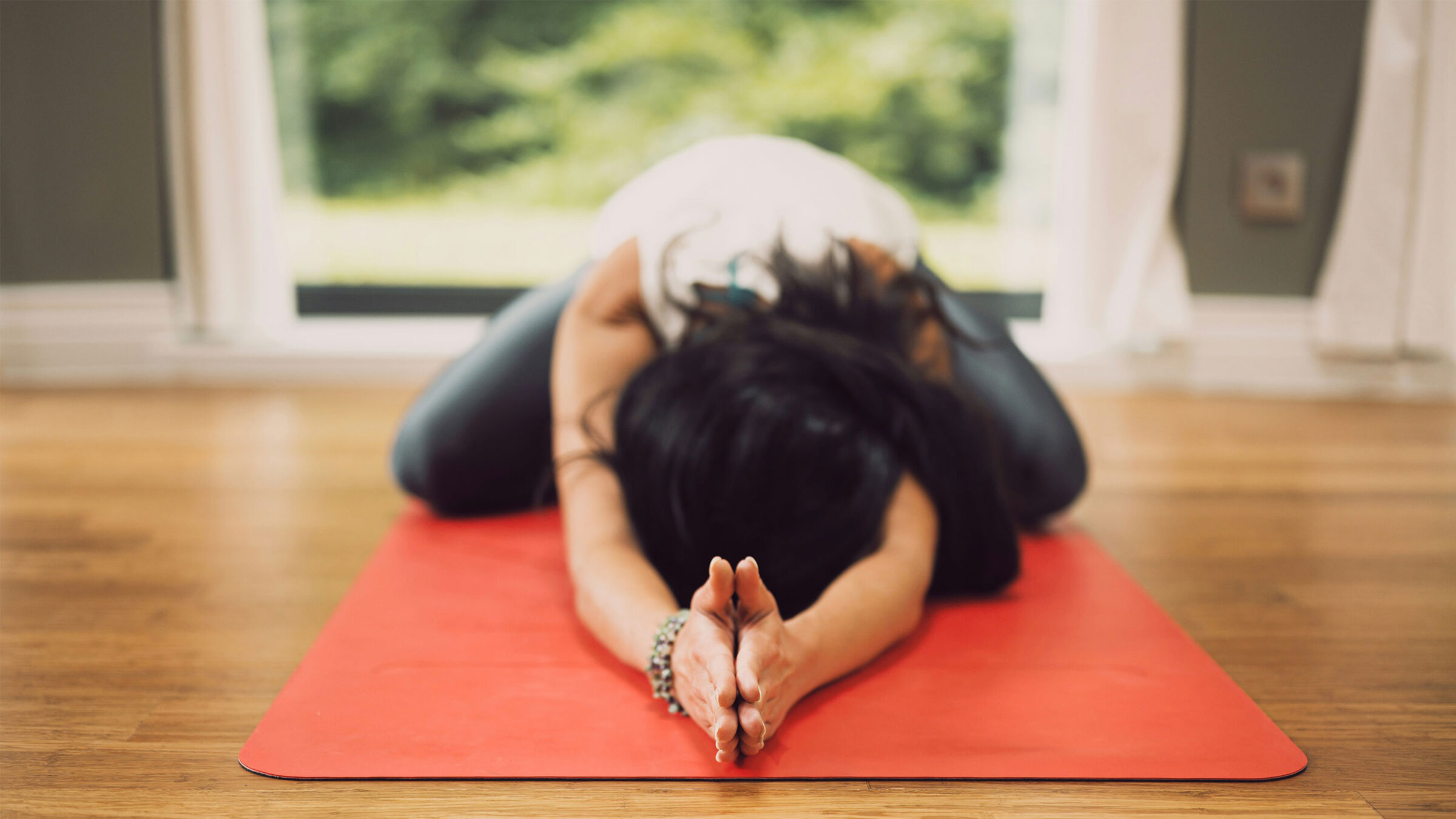 person stretching on yoga mat in child's pose, with hands forward