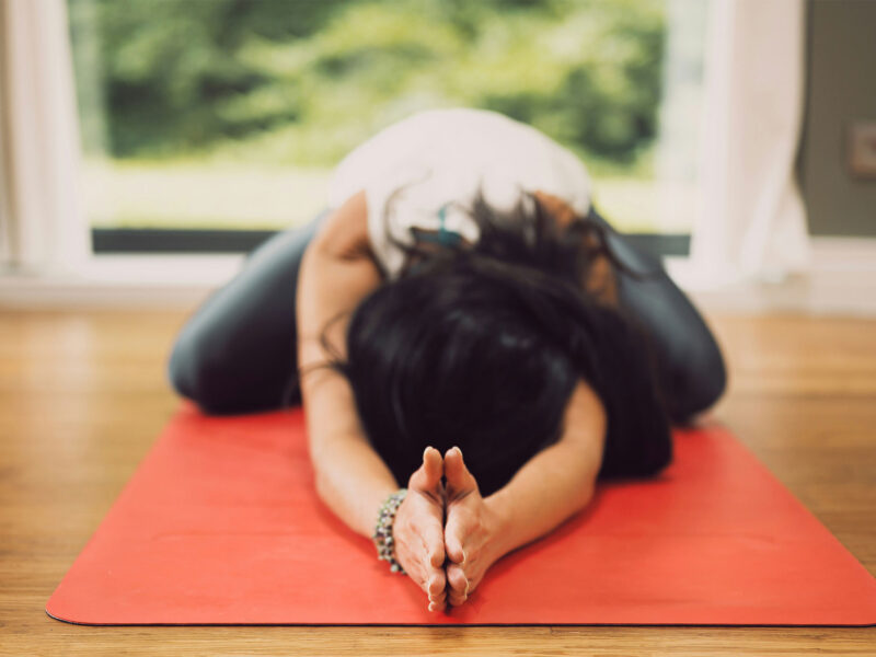 person stretching on yoga mat in child's pose, with hands forward