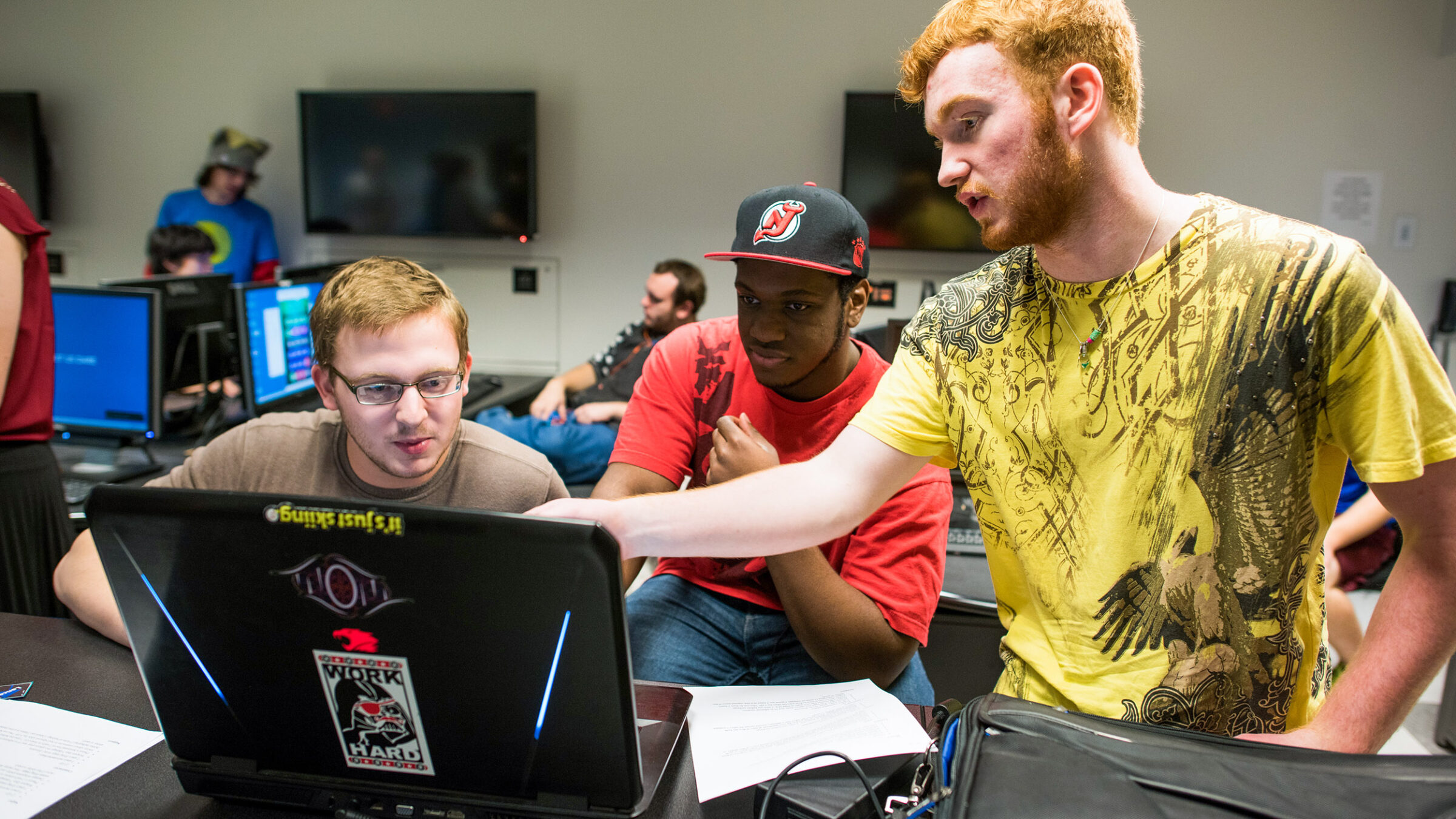 students collaborate pointing at a computer