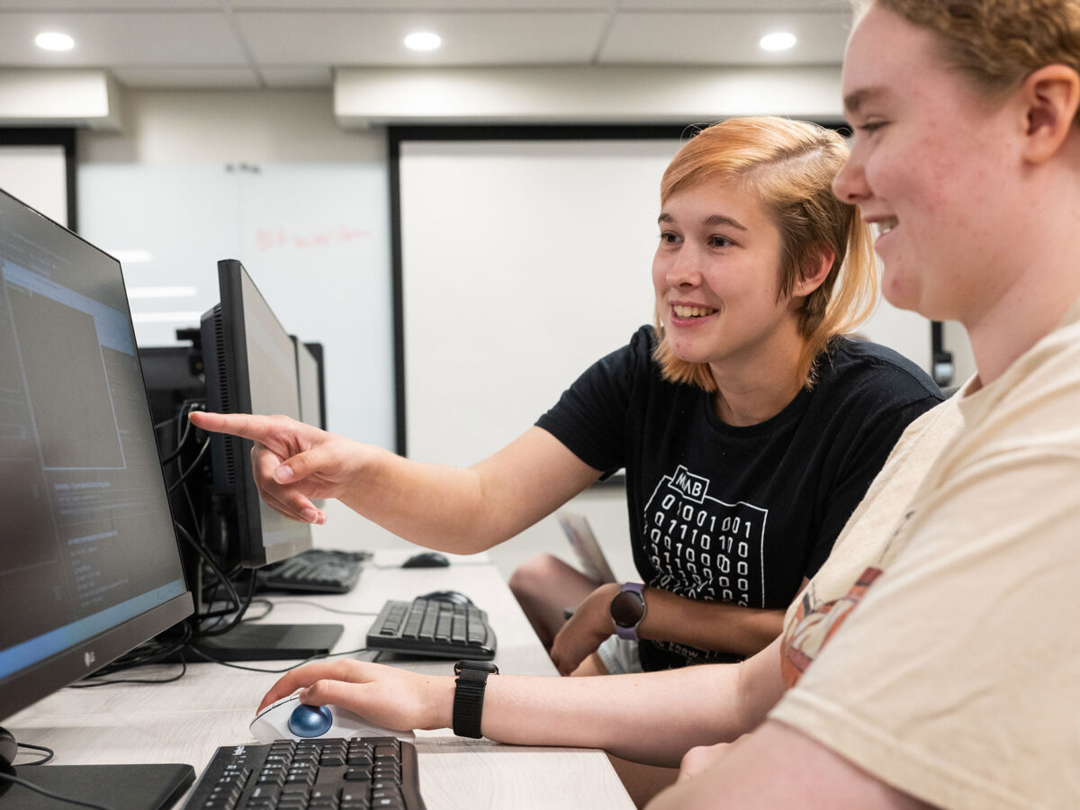 Two students learn about cybersecurity at a computer.