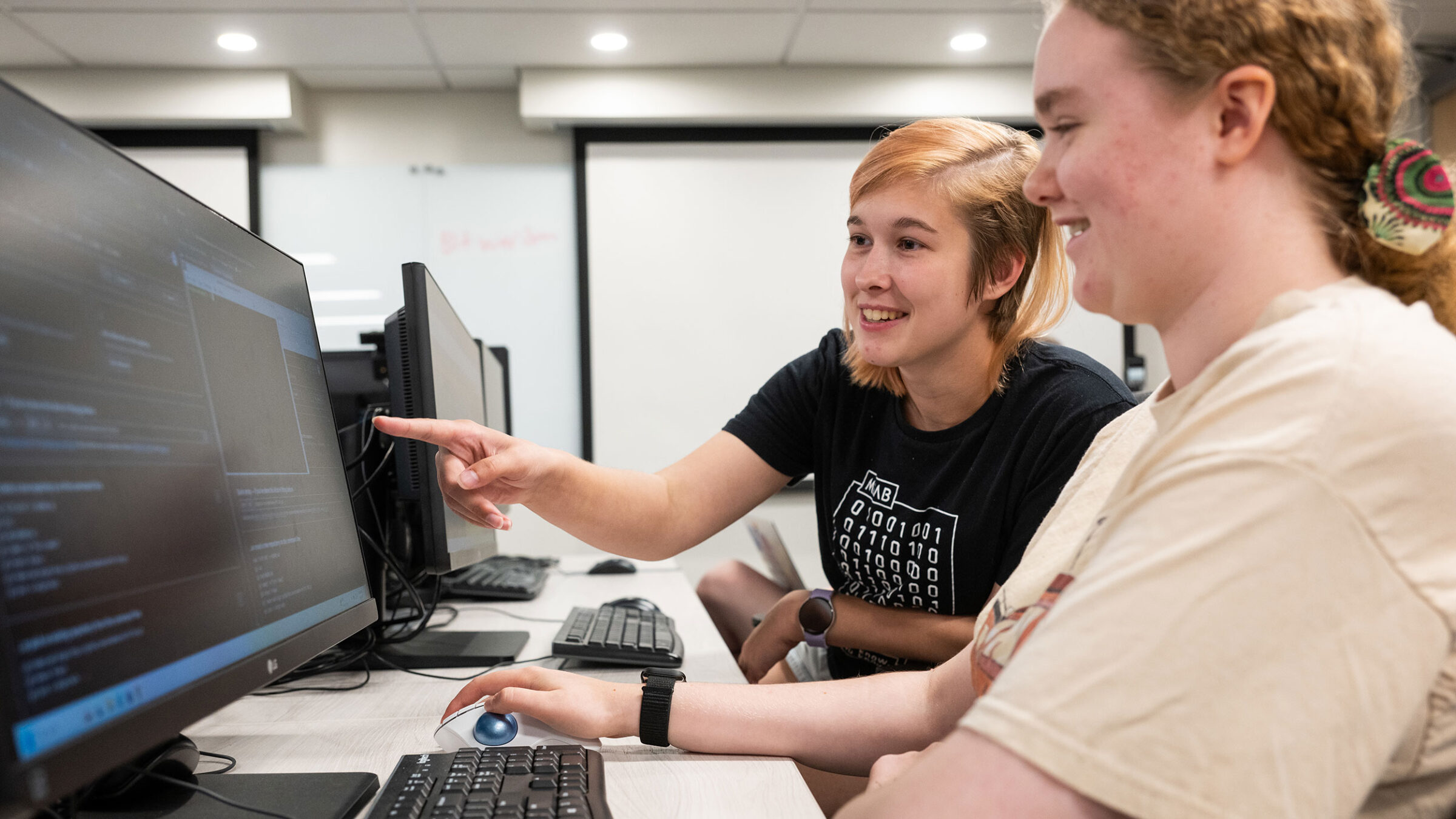 Two students learn about cybersecurity at a computer.