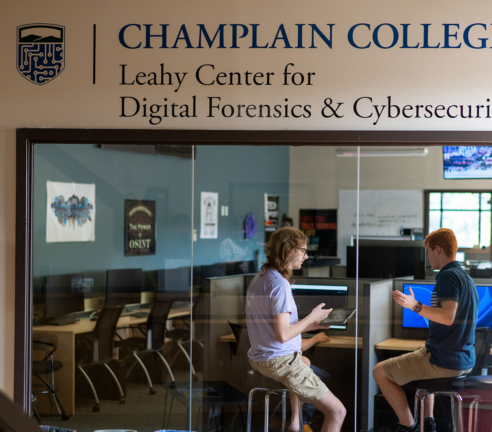 Two students collaborate behind a glass wall at the Leahy Center.