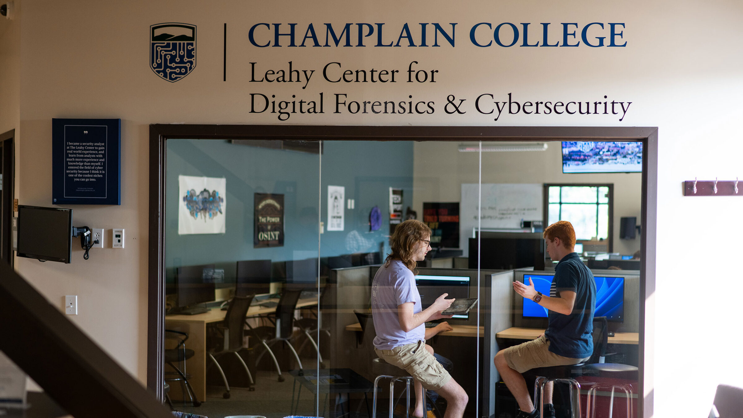 Two students collaborate behind a glass wall at the Leahy Center.