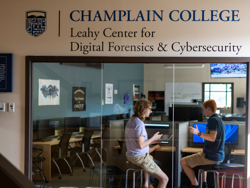 Two students collaborate behind a glass wall at the Leahy Center.