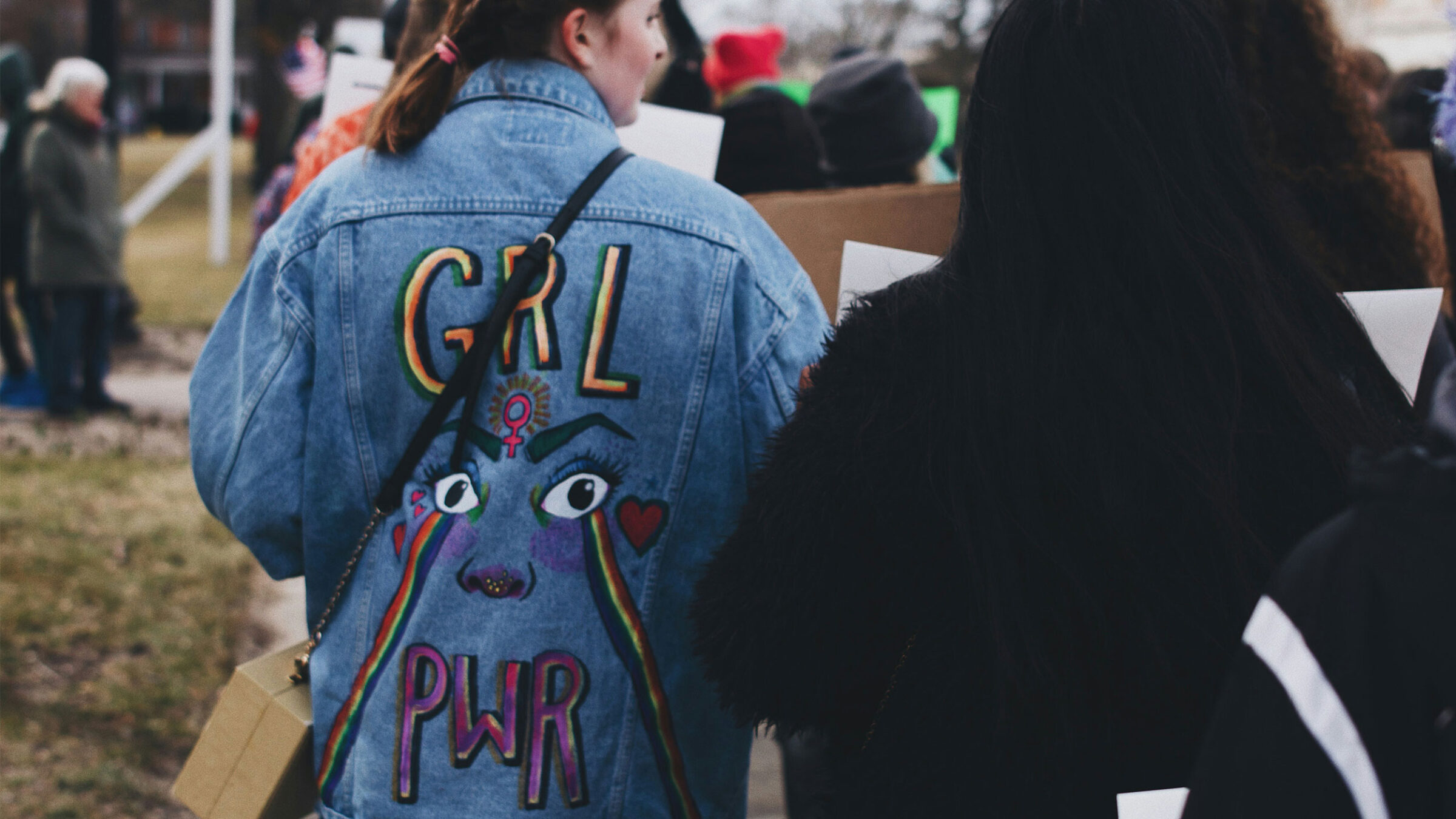 person wearing jean jacket at march that reads "grl pwr"