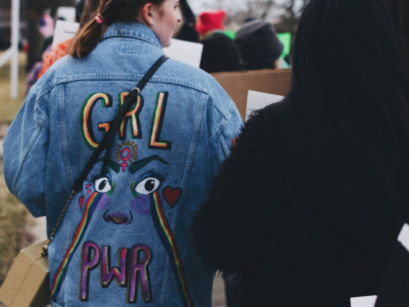 person wearing jean jacket at march that reads "grl pwr"