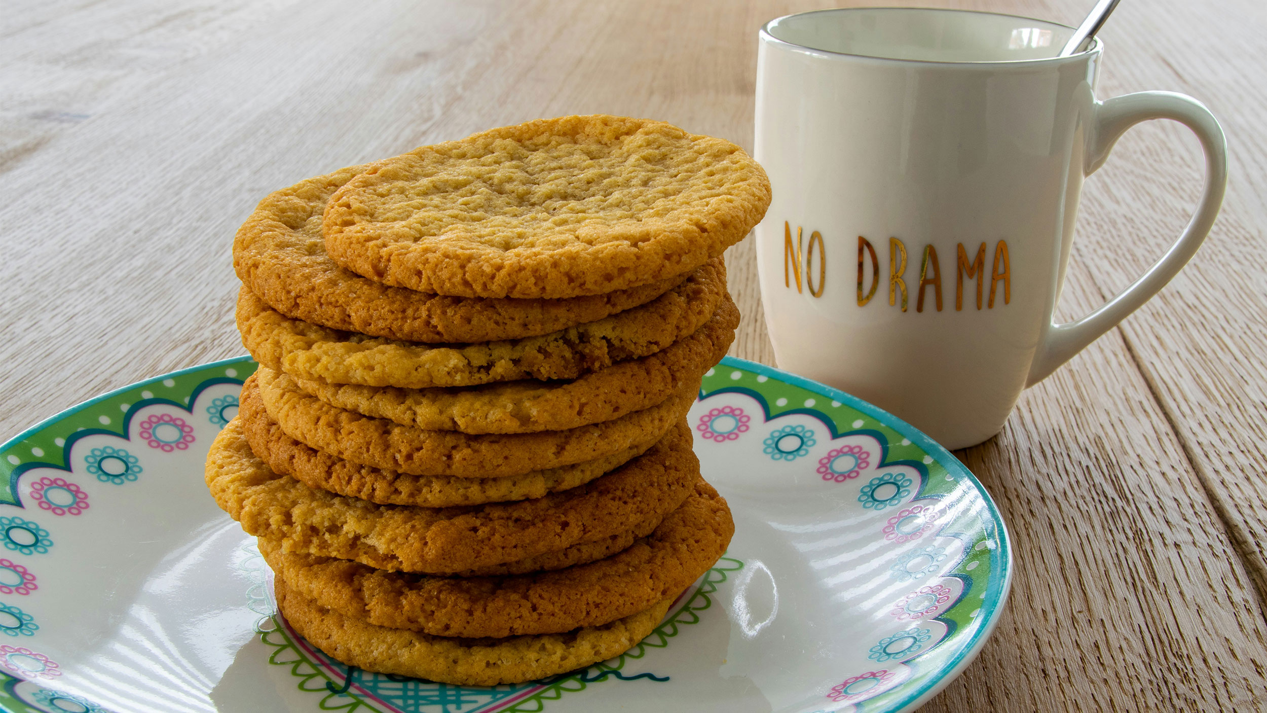 10 cookies piled on top of each other next to a mug that reads "no drama"