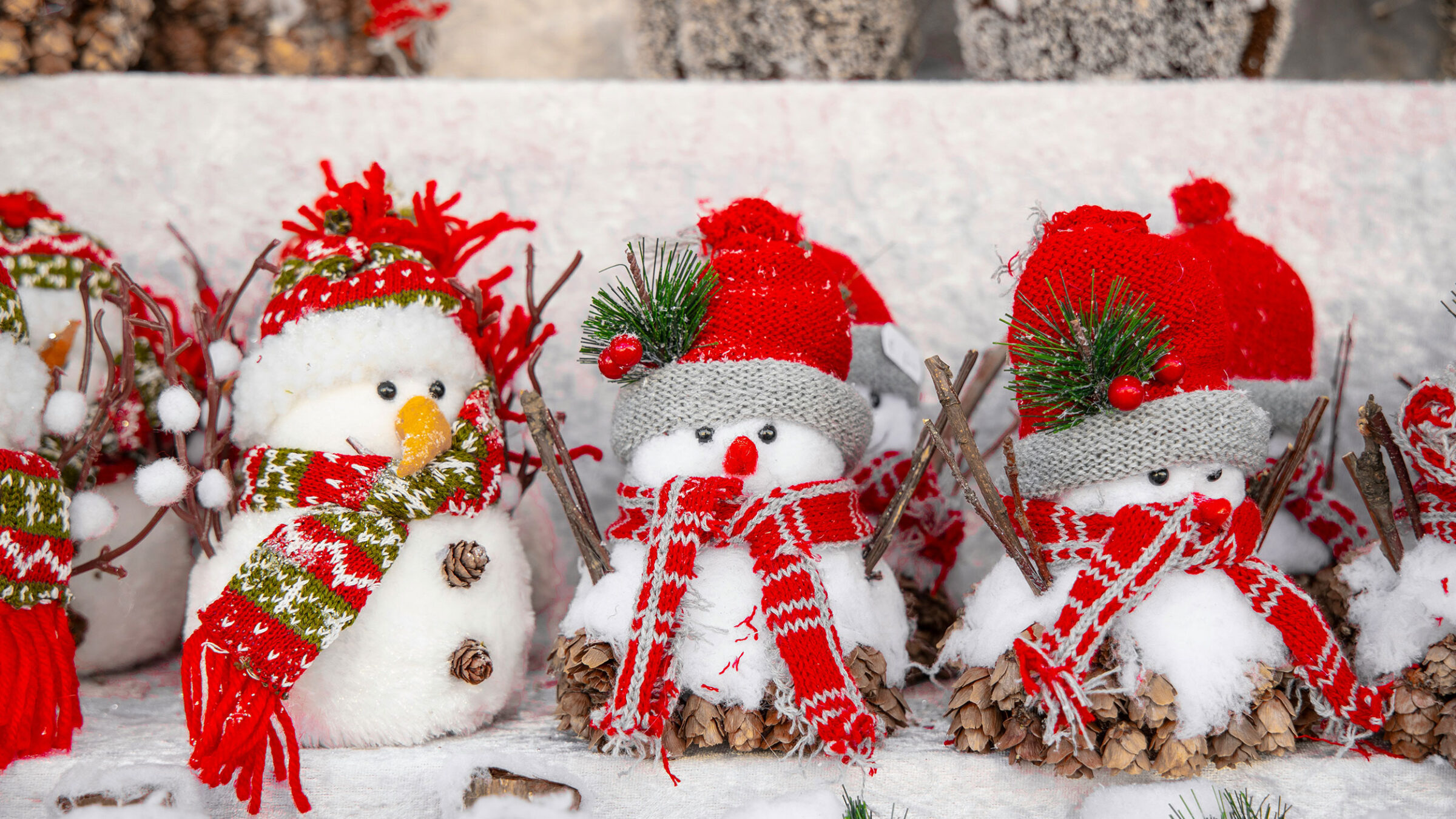 three small stuffed animal snowmen dressed in red winter hats and scarves