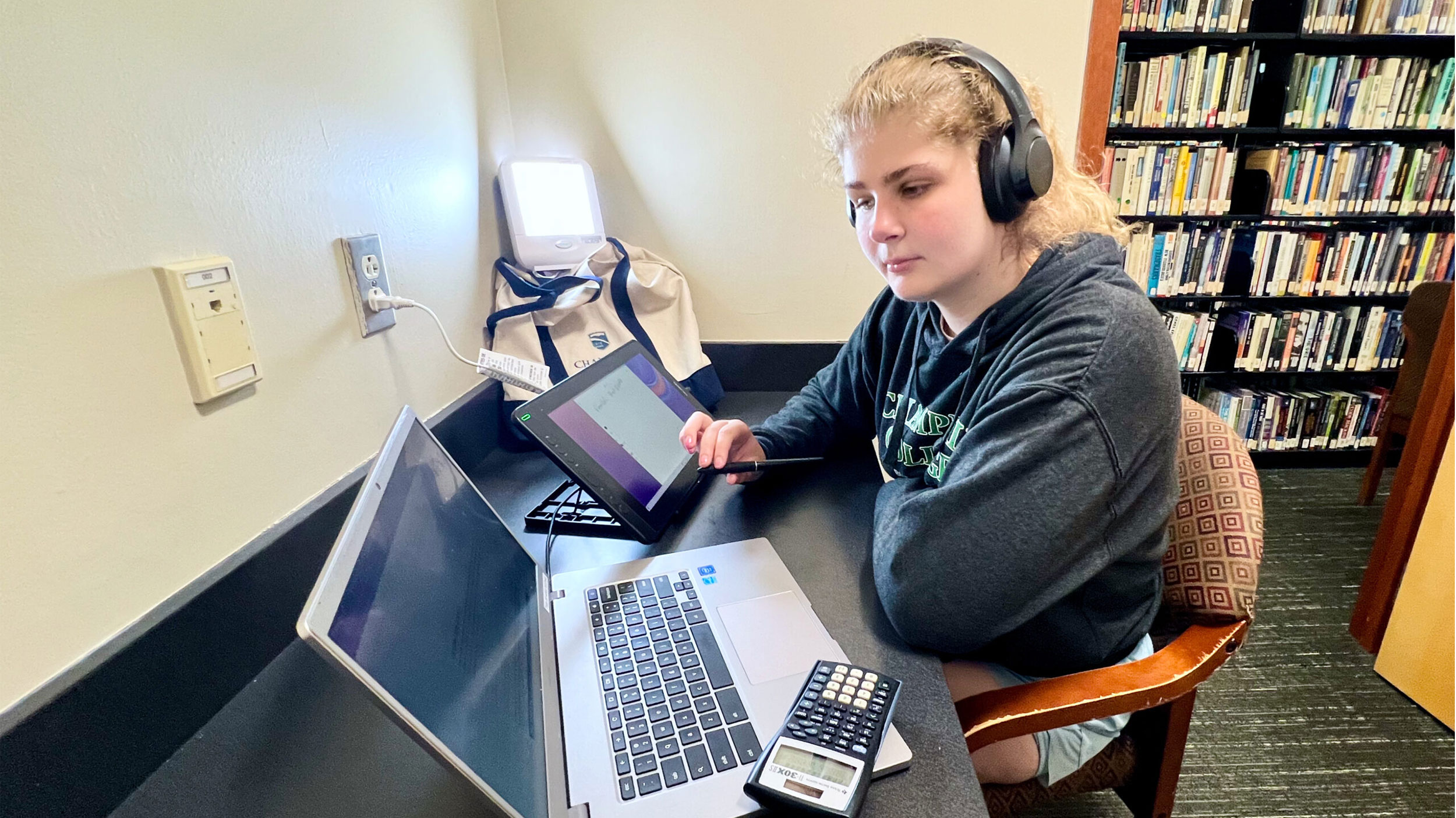 student sits at desk with laptop and a happy light