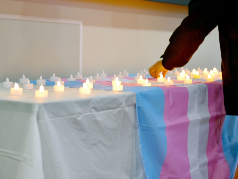 electric candles on table with trans flag laying across it