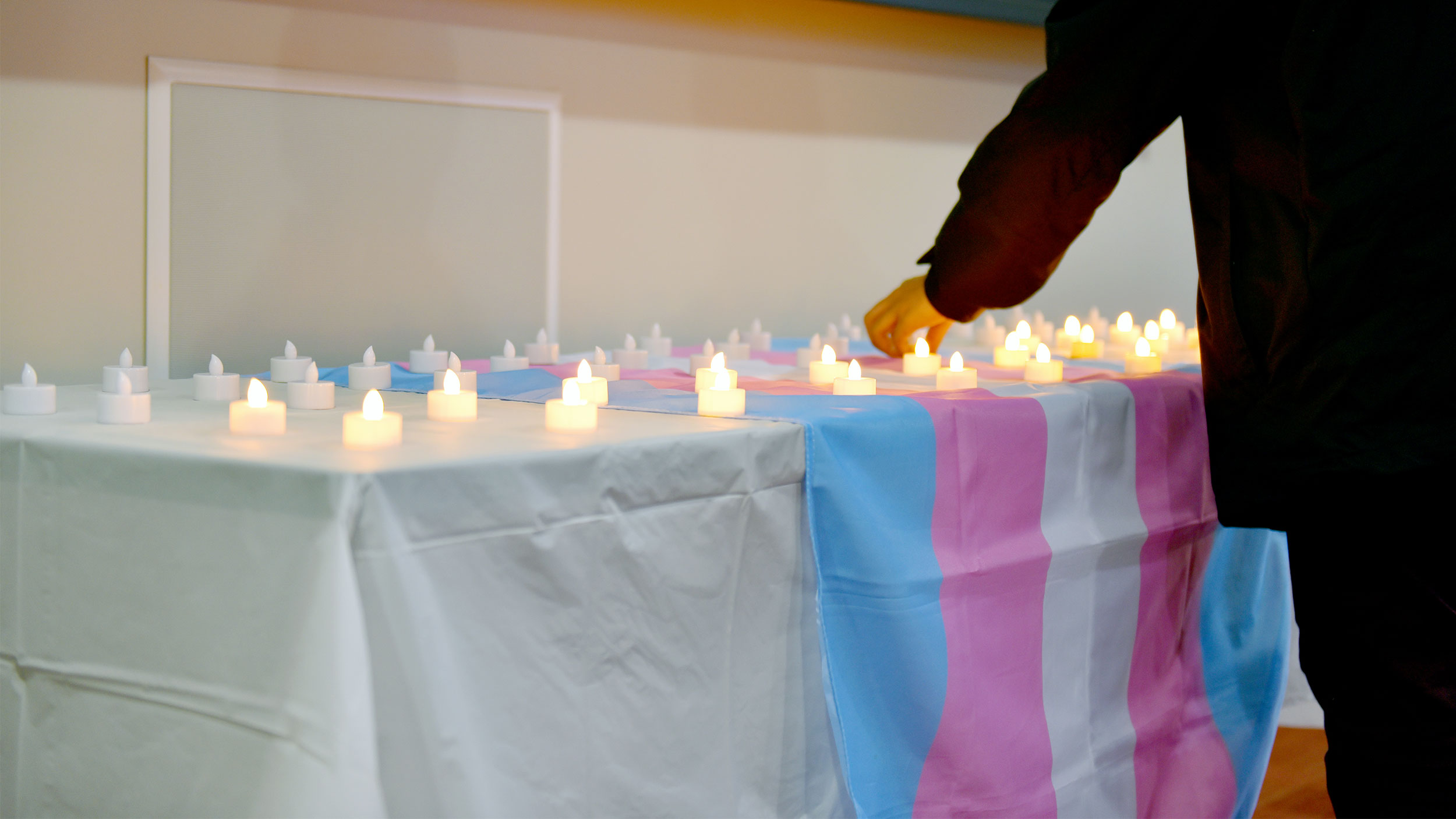 electric candles on table with trans flag laying across it