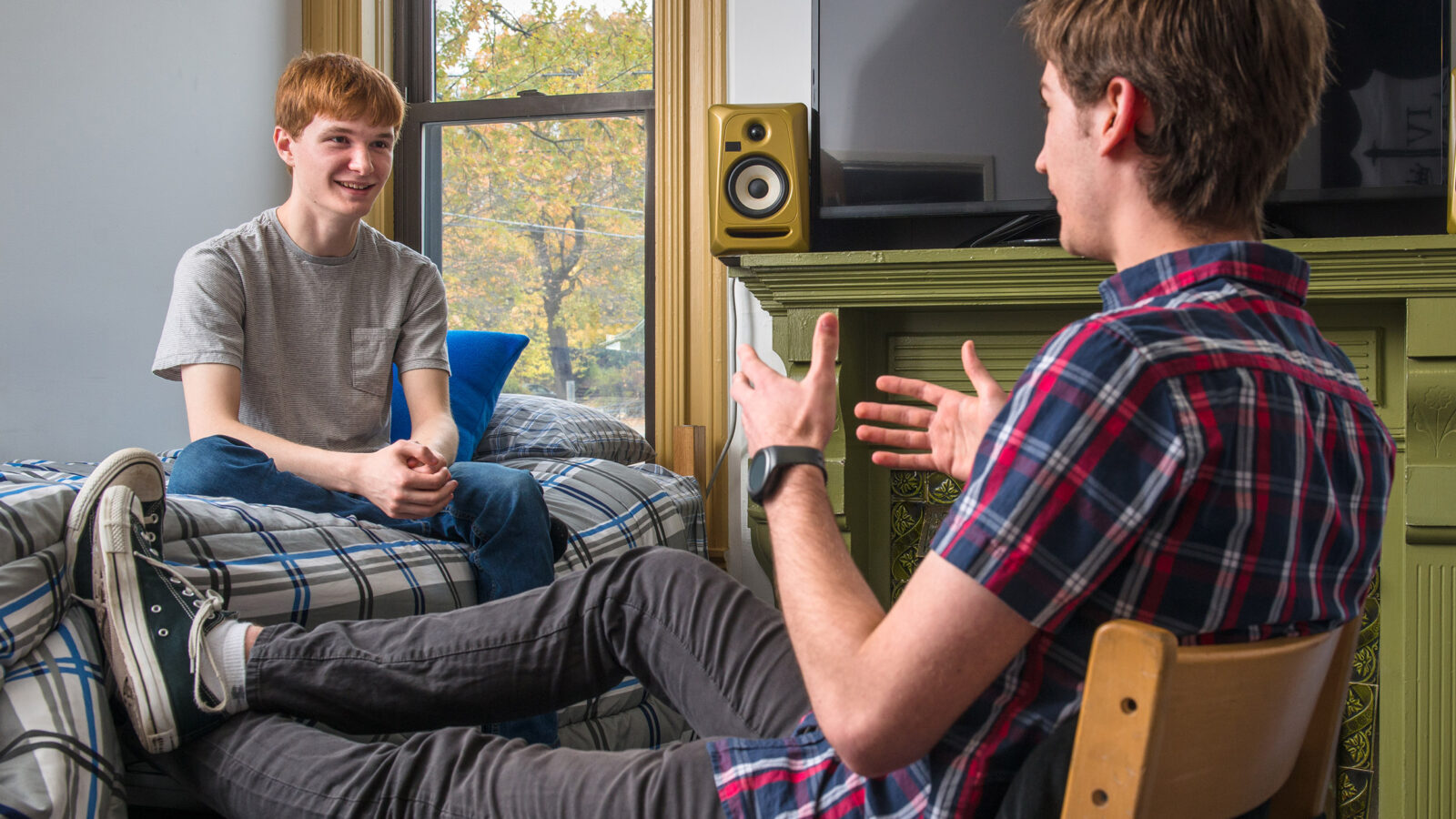 two students sit in a dorm room talking casually