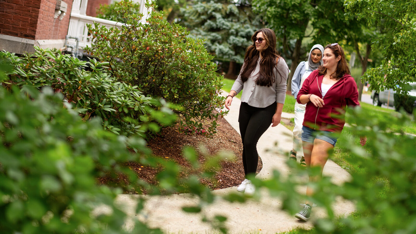 students walking around the outside of a residence hall, greenery