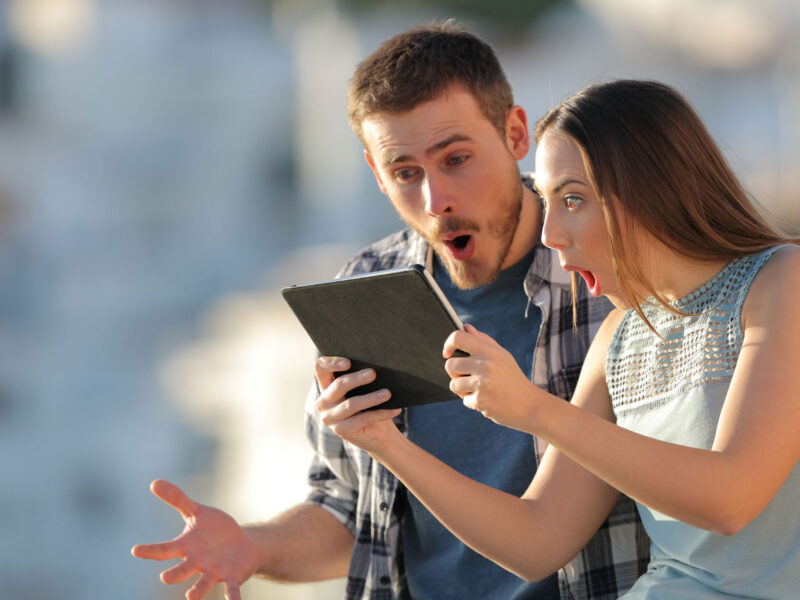 two people look very surprised while looking at a tablet