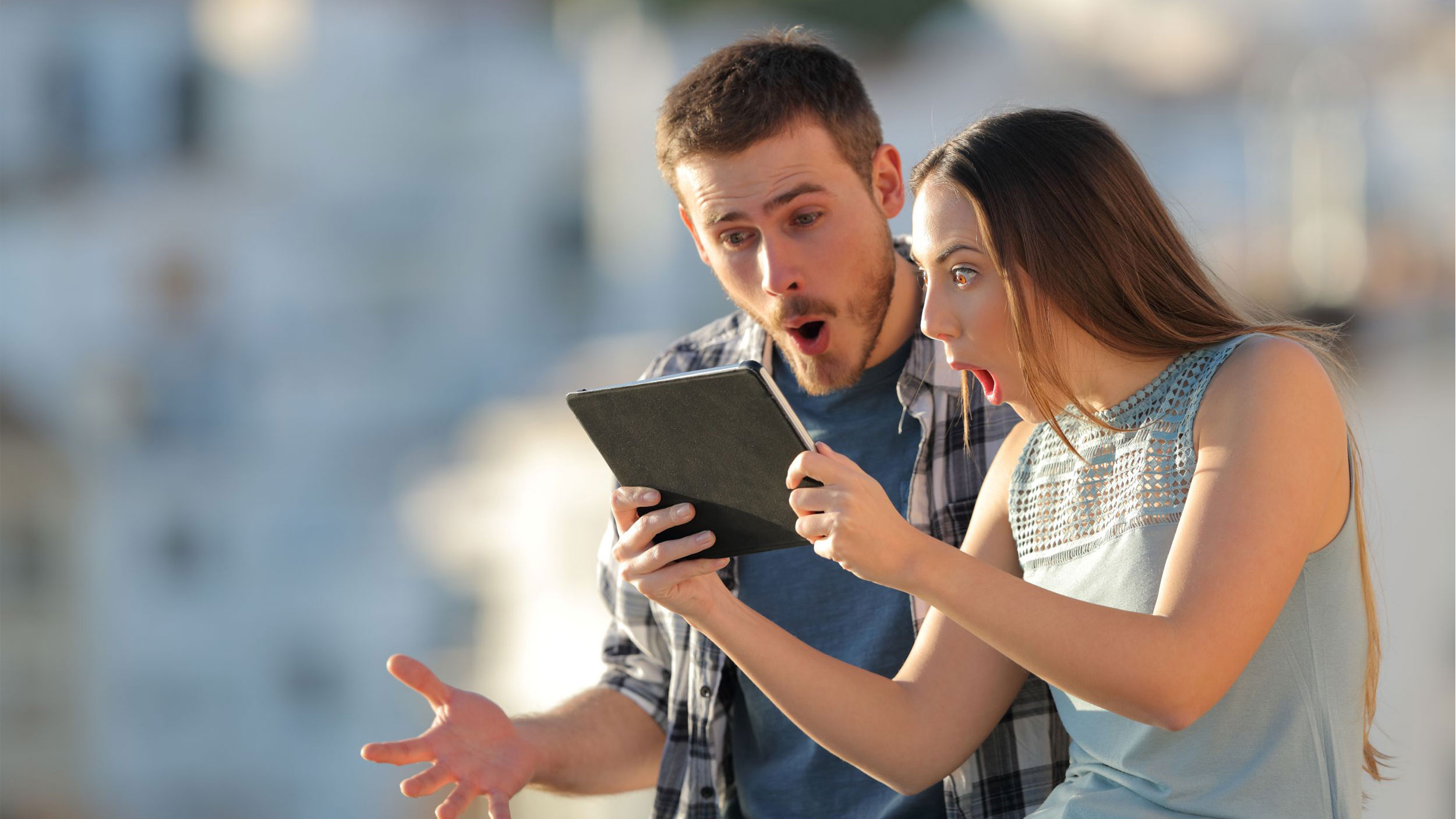 two people look very surprised while looking at a tablet