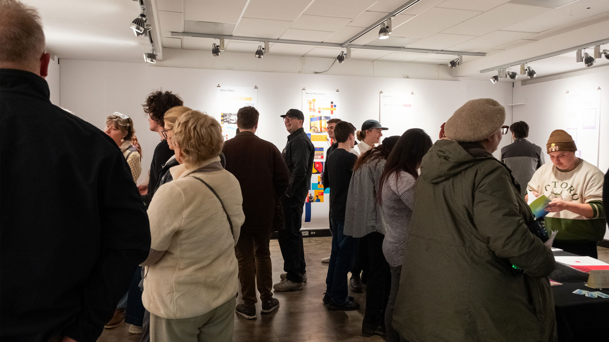 people gathering in the art gallery talking and looking at art on the walls